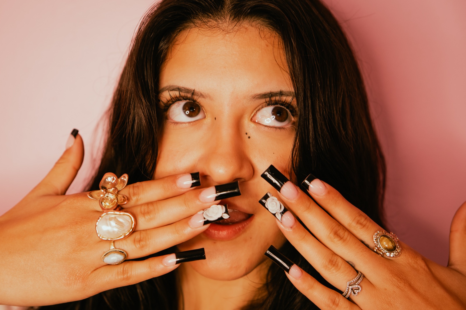Close-up of a client's long black-and-white nail art with gold rings